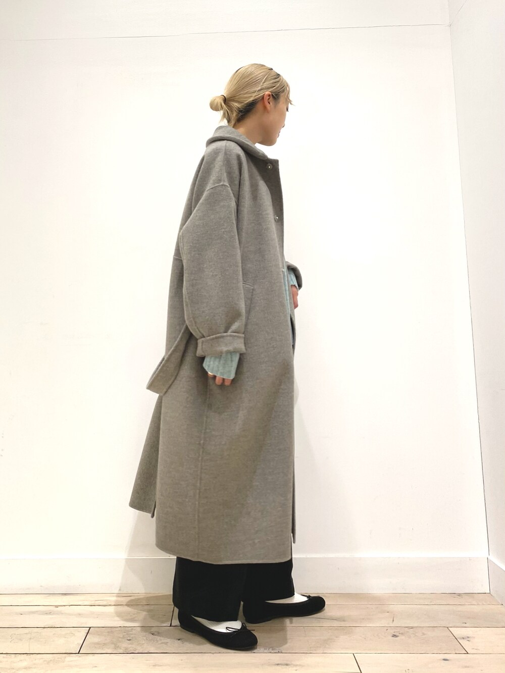 グリーン系のニット/セーター、グレー系のステンカラーコート、ブラック系のバレエシューズを着用したレディースの秋コーディネートの4枚目の写真