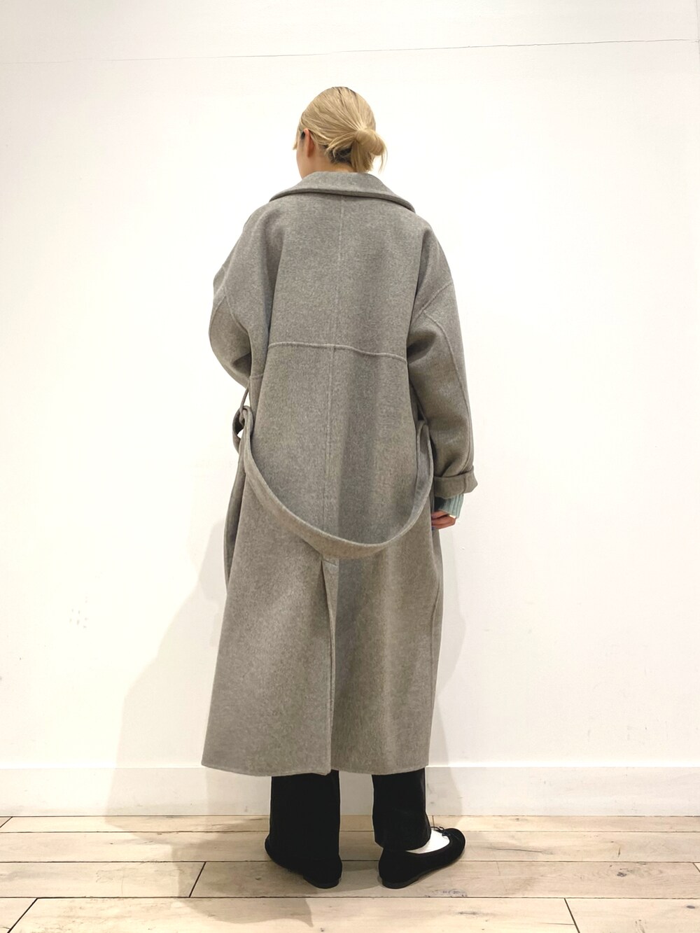 グリーン系のニット/セーター、グレー系のステンカラーコート、ブラック系のバレエシューズを着用したレディースの秋コーディネートの5枚目の写真