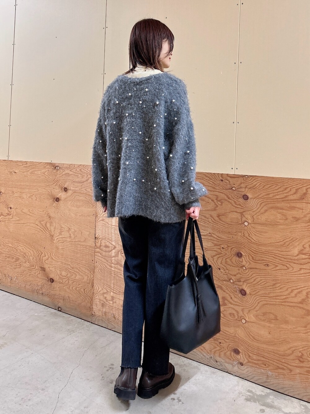 グレー系のカーディガン/ボレロ、ブラック系のデニムパンツ、ホワイト系のニット/セーターを着用したレディースの冬コーディネートの3枚目の写真
