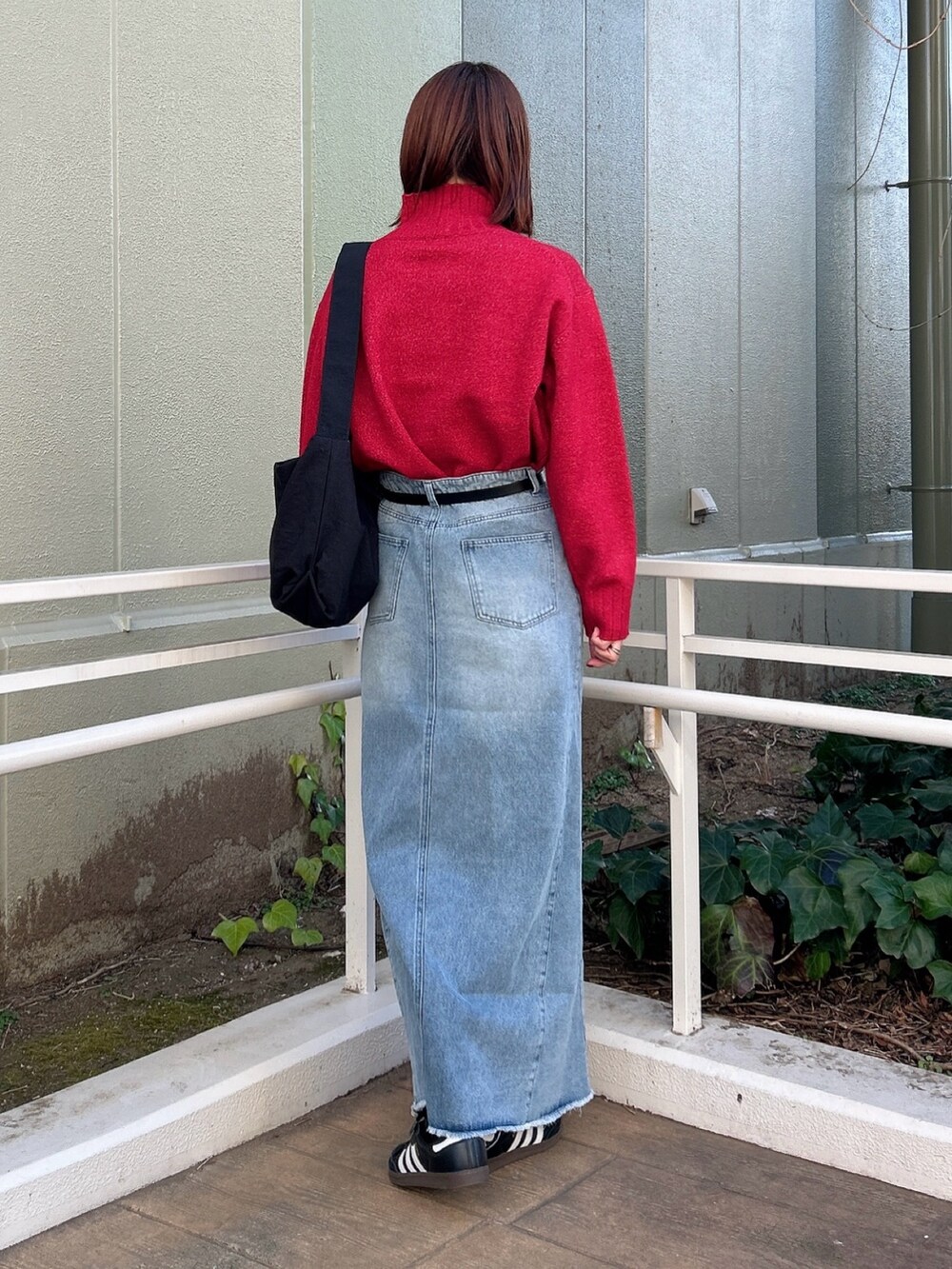 レッド系のニット/セーター、ブラック系のショルダーバッグ、ブルー系のスカートを着用したレディースの冬コーディネートの5枚目の写真