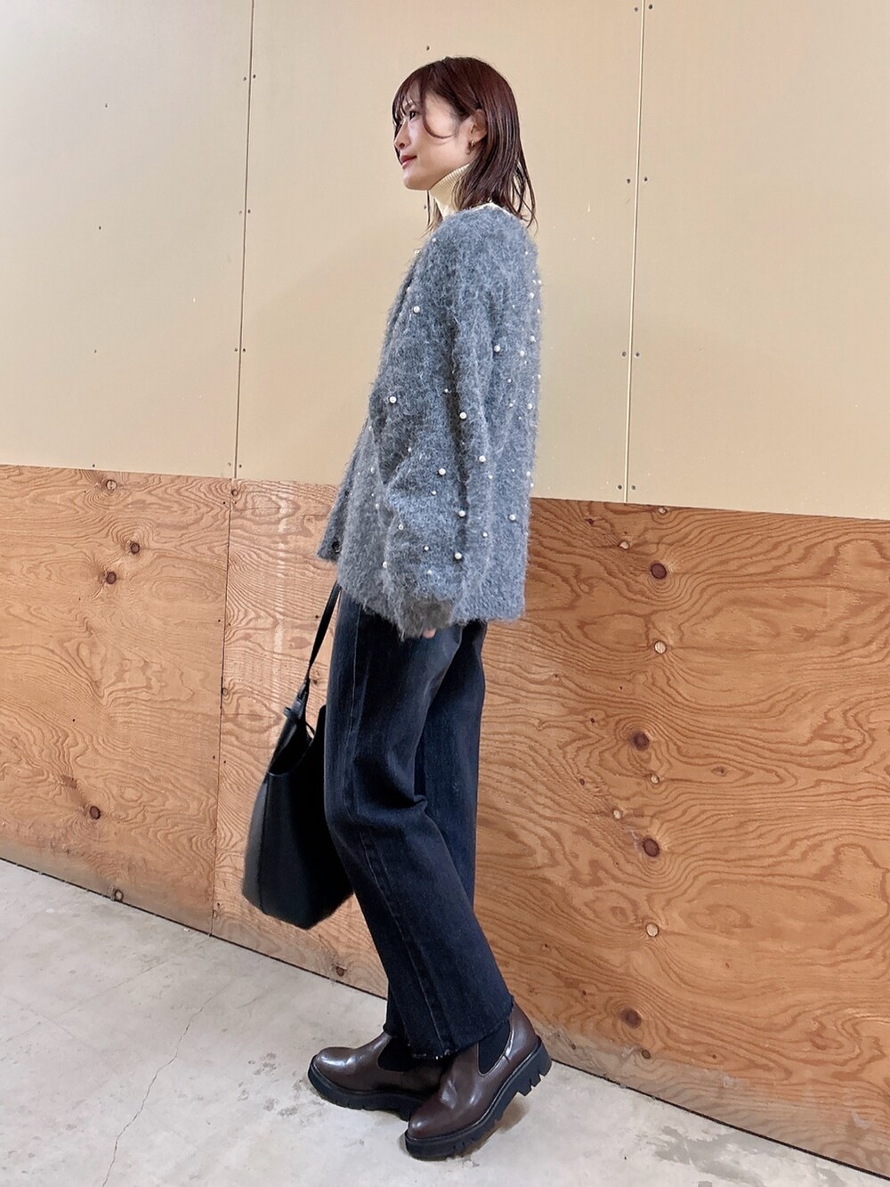 グレー系のカーディガン/ボレロ、ブラック系のデニムパンツ、ホワイト系のニット/セーターを着用したレディースの冬コーディネートの2枚目の写真
