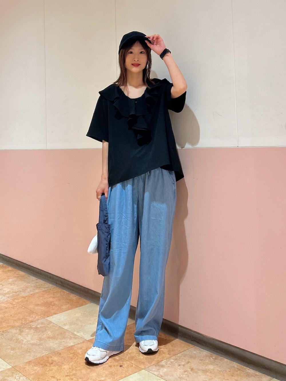 ブルー系のデニムパンツ、ブラック系のタンクトップ、ブルー系のエコバッグ/サブバッグを着用したレディースの春コーディネートの2枚目の写真