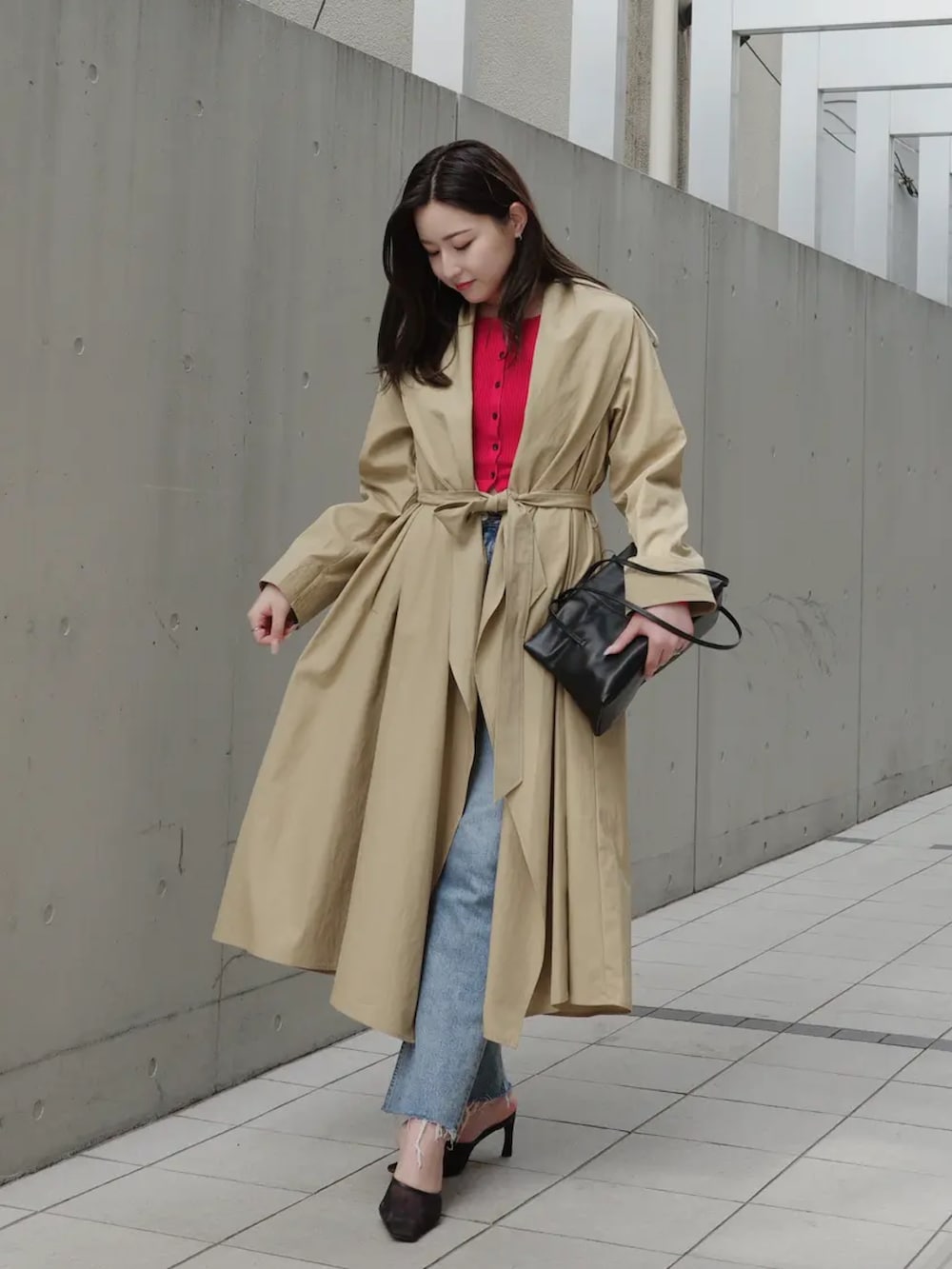 ベージュ系のトレンチコート、レッド系のカーディガン/ボレロ、ブルー系のデニムパンツを着用したレディースの冬コーディネートの2枚目の写真