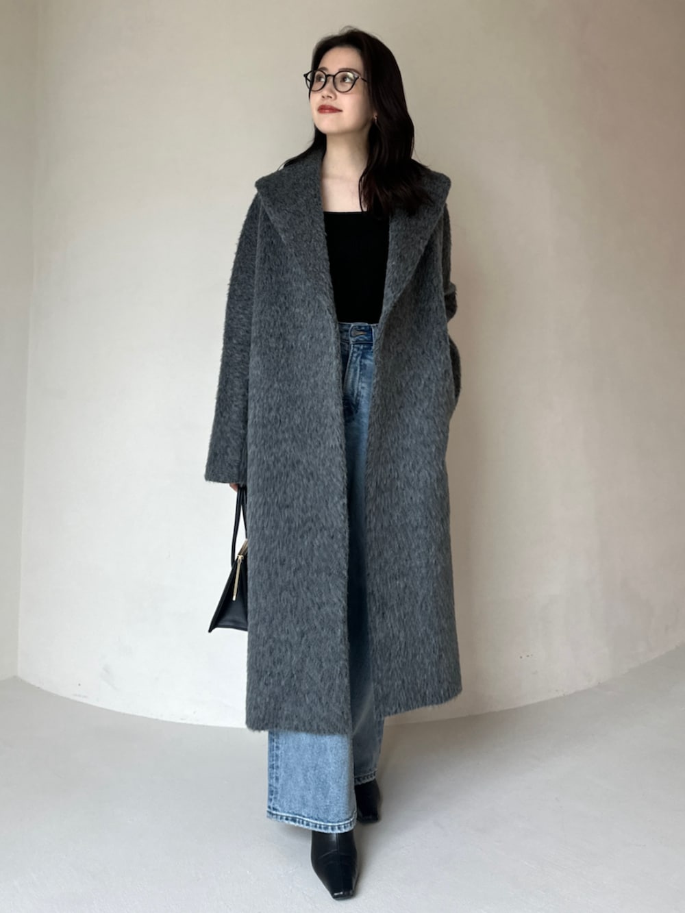 グレー系のその他アウター、ブルー系のデニムパンツ、ブラック系のハンドバッグを着用したレディースの冬コーディネートの3枚目の写真