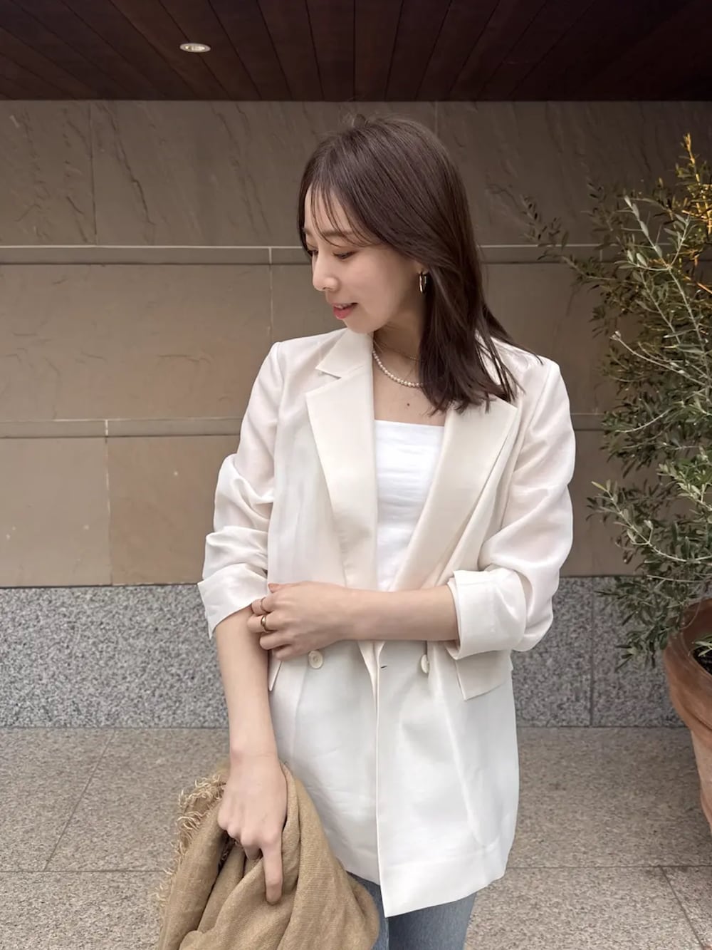 ブルー系のデニムパンツ、ホワイト系のテーラードジャケットを着用したレディースの春コーディネートの3枚目の写真