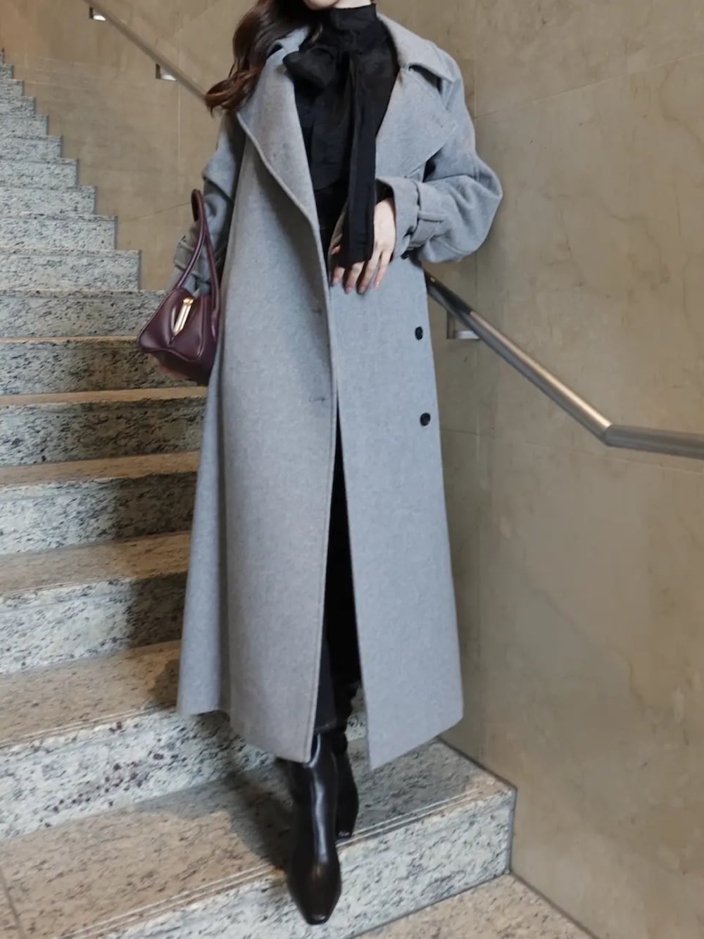 グレー系のトレンチコート、レッド系のボストンバッグ、ブラック系のシャツ/ブラウスを着用したレディースの秋コーディネートの2枚目の写真