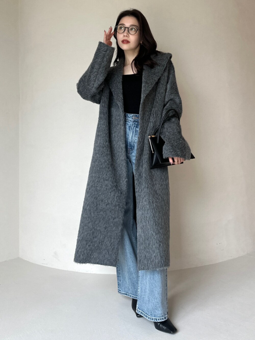 グレー系のその他アウター、ブルー系のデニムパンツ、ブラック系のハンドバッグを着用したレディースの冬コーディネートの2枚目の写真