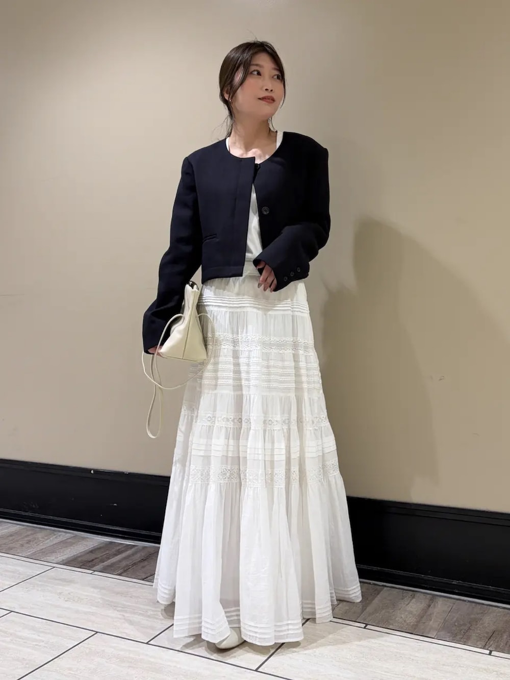 ブルー系のノーカラージャケット、ホワイト系のスカートを着用したレディースの春コーディネートの3枚目の写真