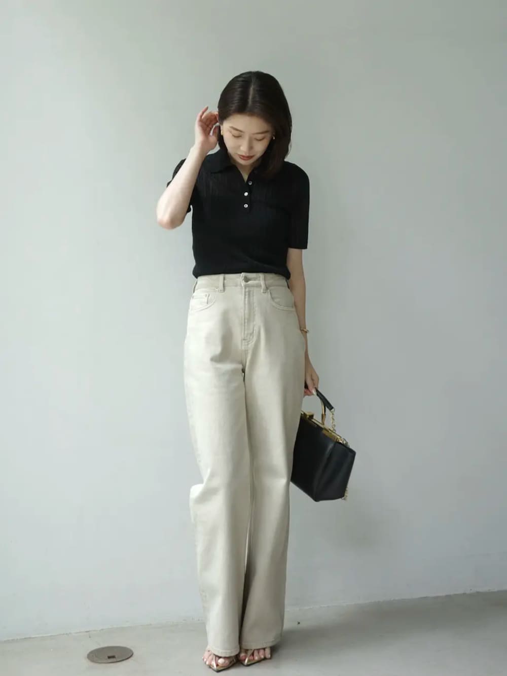 ベージュ系のデニムパンツ、ブラック系のニット/セーターを着用したレディースの夏コーディネートの2枚目の写真