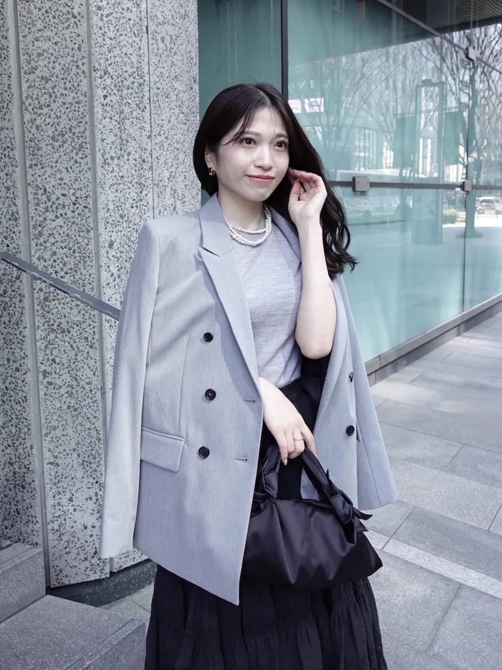 グレー系のテーラードジャケット、グレー系のその他トップス、ブラック系のスカートを着用したレディースの春コーディネートの3枚目の写真