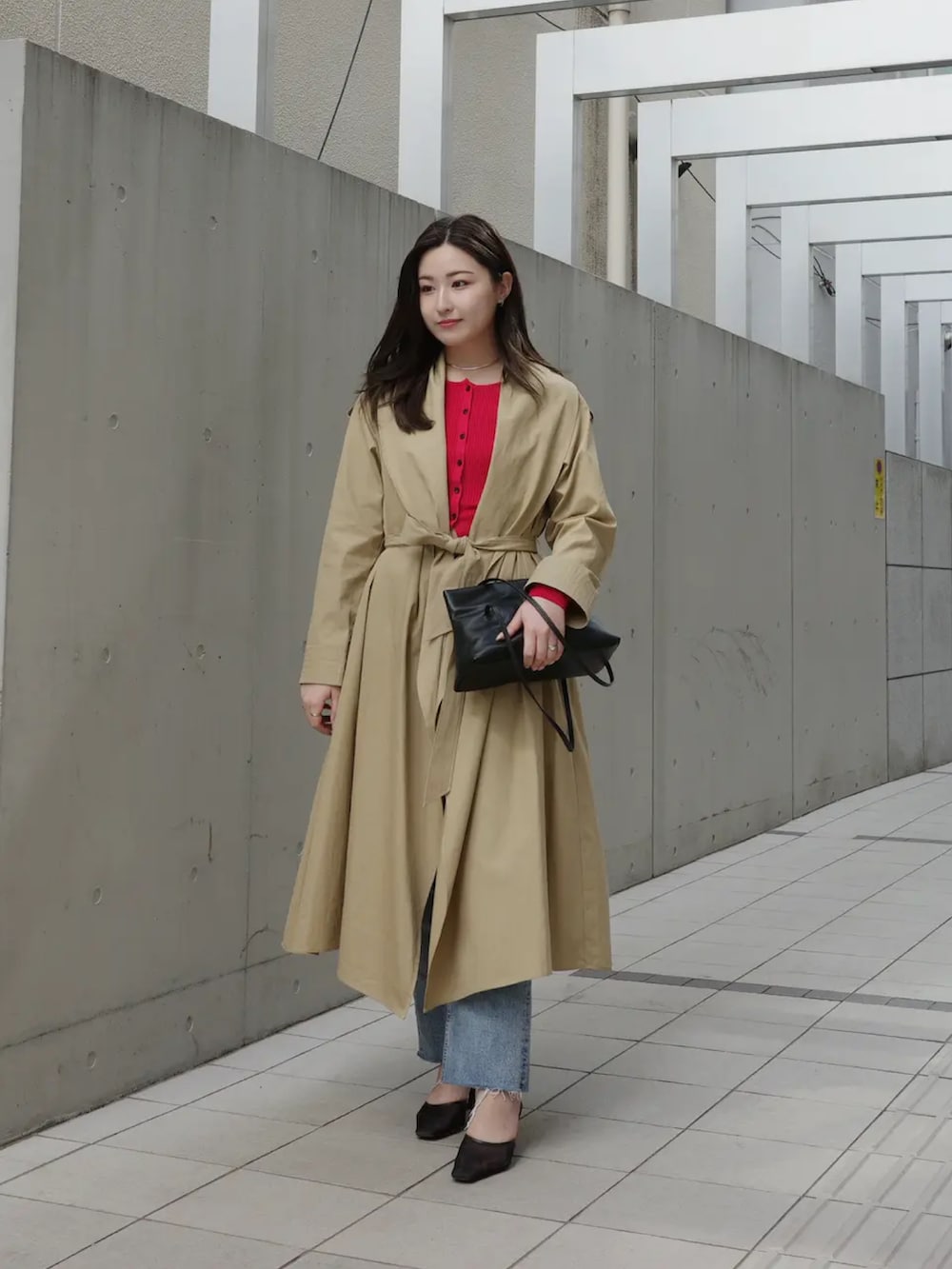 ベージュ系のトレンチコート、レッド系のカーディガン/ボレロ、ブルー系のデニムパンツを着用したレディースの冬コーディネートの4枚目の写真