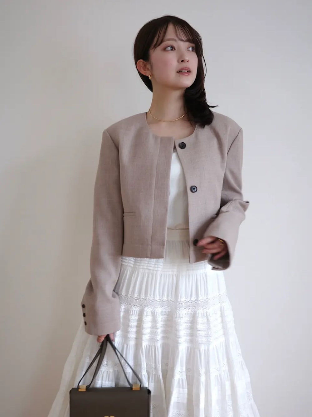 ベージュ系のノーカラージャケット、ホワイト系のスカートを着用したレディースの冬コーディネートの2枚目の写真