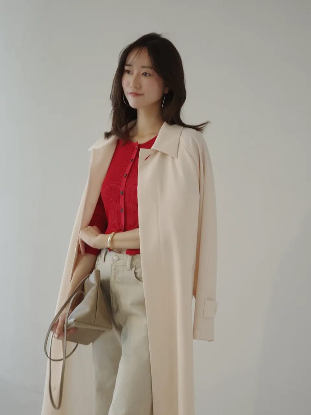 レッド系のカーディガン/ボレロ、ベージュ系のデニムパンツ、ピンク系のステンカラーコートを着用したレディースの春コーディネートの3枚目の写真