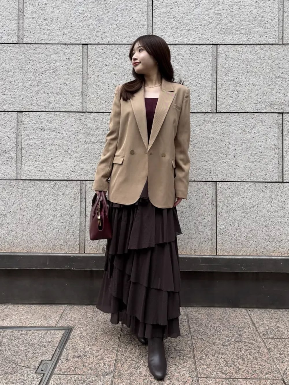 ブラウン系のスカート、ブラウン系のブーツ、ベージュ系のテーラードジャケットを着用したレディースの冬コーディネートの2枚目の写真