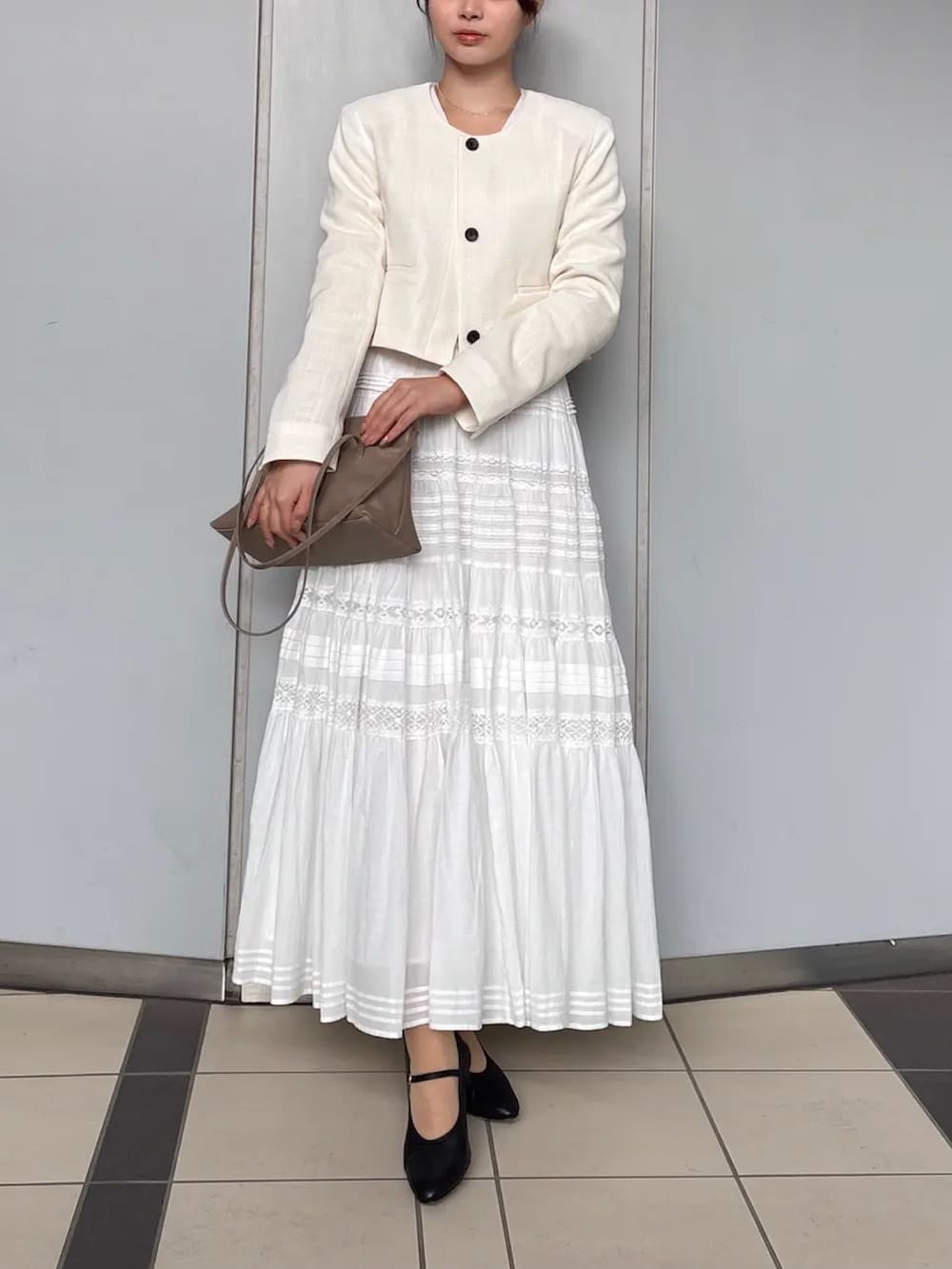 ホワイト系のノーカラージャケット、ホワイト系のスカートを着用したレディースの春コーディネートの2枚目の写真