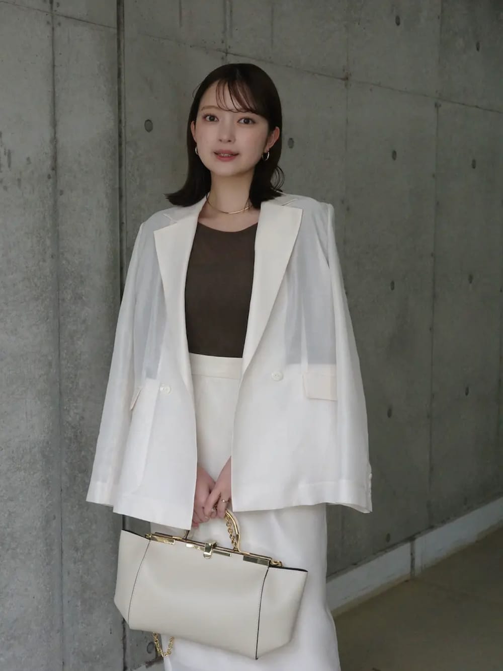 ホワイト系のテーラードジャケット、ブラウン系のTシャツ/カットソー、ホワイト系のスカートを着用したレディースの春コーディネートの2枚目の写真