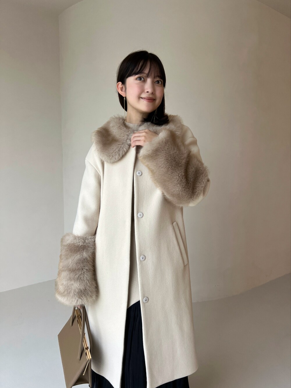 ベージュ系のその他アウター、ベージュ系のワンピース、ベージュ系のハンドバッグを着用したレディースの冬コーディネートの4枚目の写真