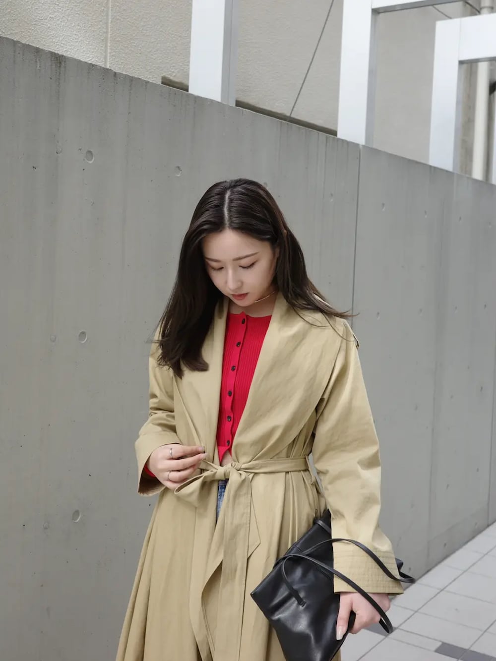 ベージュ系のトレンチコート、レッド系のカーディガン/ボレロ、ブルー系のデニムパンツを着用したレディースの冬コーディネートの3枚目の写真