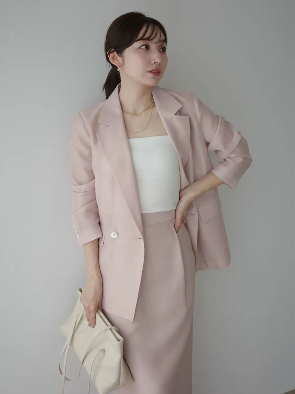 ピンク系のテーラードジャケット、ピンク系のスカートを着用したレディースの春コーディネートの2枚目の写真