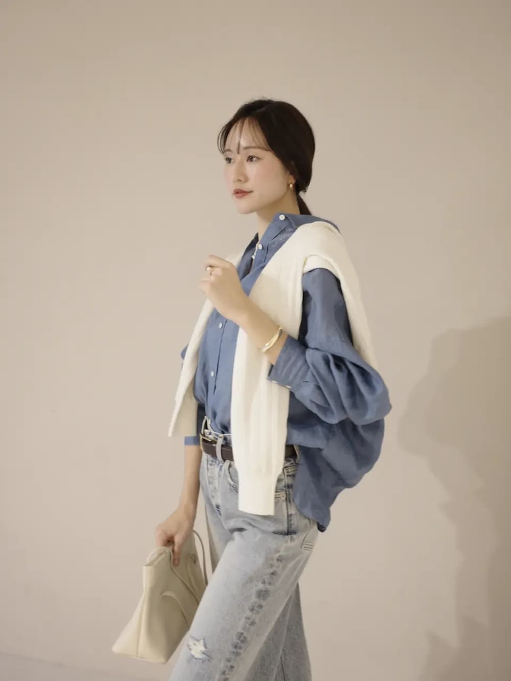 ブルー系のシャツ/ブラウス、ホワイト系のカーディガン/ボレロ、ブルー系のデニムパンツを着用したレディースの冬コーディネートの4枚目の写真