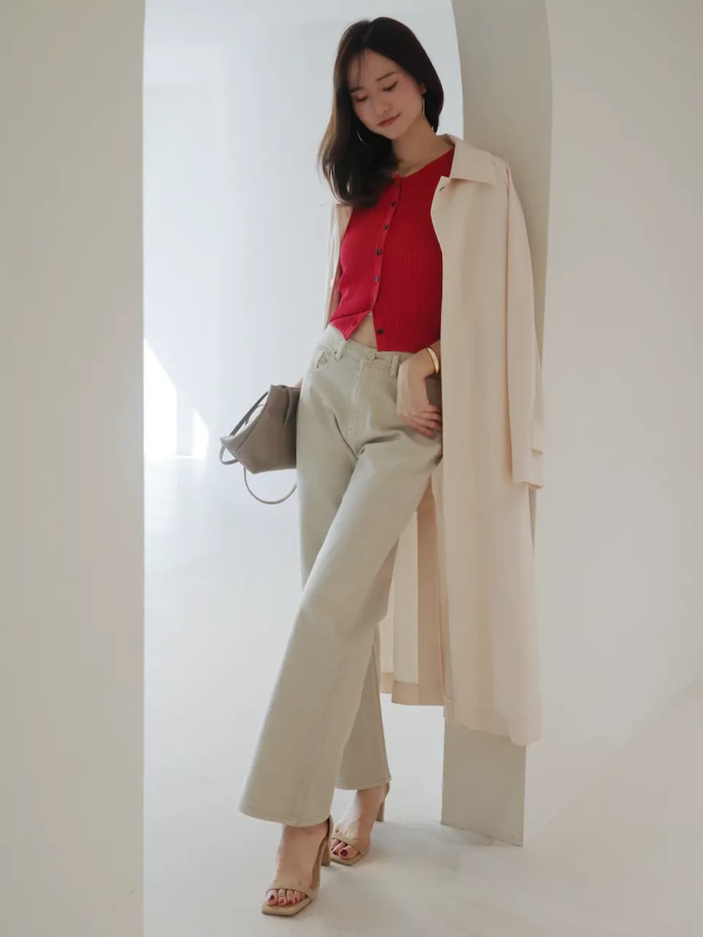 レッド系のカーディガン/ボレロ、ベージュ系のデニムパンツ、ピンク系のステンカラーコートを着用したレディースの春コーディネートの2枚目の写真