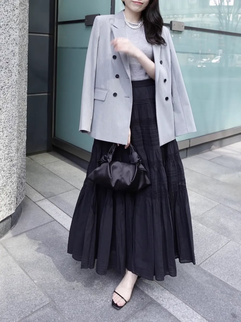 グレー系のテーラードジャケット、グレー系のその他トップス、ブラック系のスカートを着用したレディースの春コーディネートの2枚目の写真
