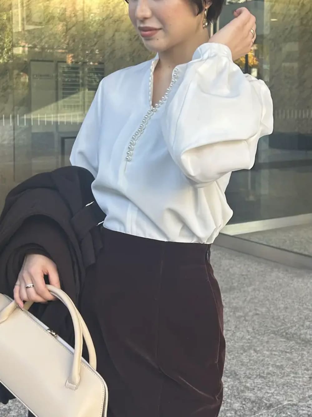 ブラウン系のトレンチコート、ホワイト系のシャツ/ブラウス、ブラウン系のスカートを着用したレディースの冬コーディネートの2枚目の写真