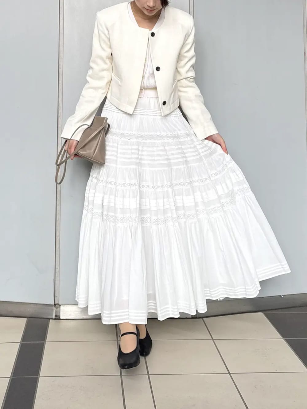 ホワイト系のノーカラージャケット、ホワイト系のスカートを着用したレディースの春コーディネートの3枚目の写真