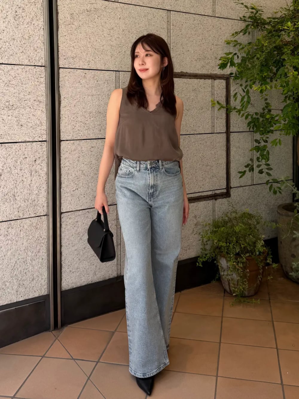 ブラック系のハンドバッグ、ブルー系のデニムパンツ、グレー系のTシャツ/カットソーを着用したレディースの夏コーディネートの3枚目の写真