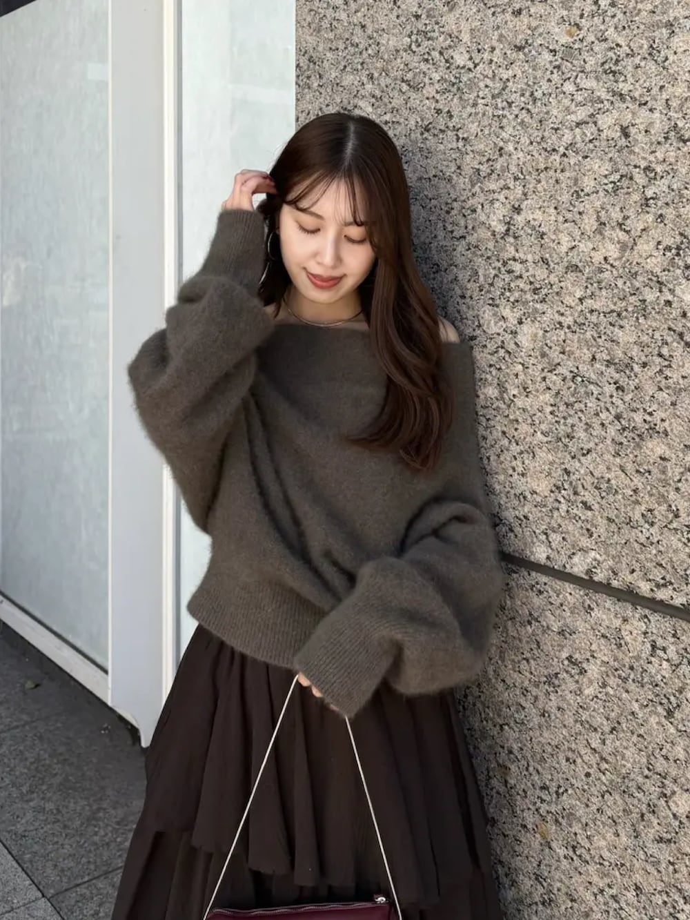 ブラウン系のニット/セーター、ブラウン系のスカート、レッド系のショルダーバッグを着用したレディースの冬コーディネートの2枚目の写真