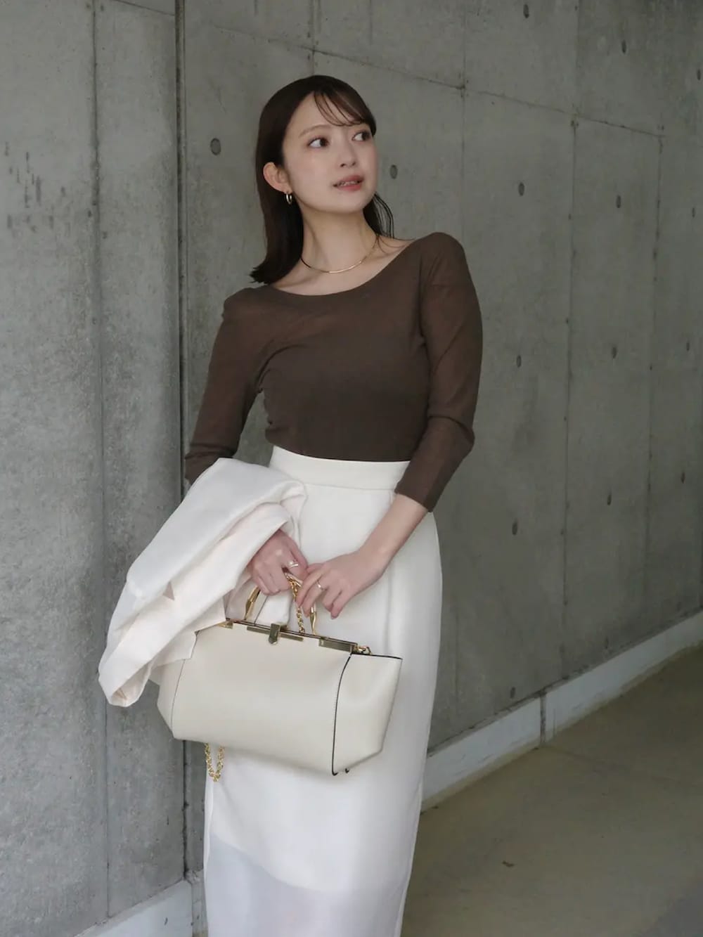 ホワイト系のテーラードジャケット、ブラウン系のTシャツ/カットソー、ホワイト系のスカートを着用したレディースの春コーディネートの4枚目の写真