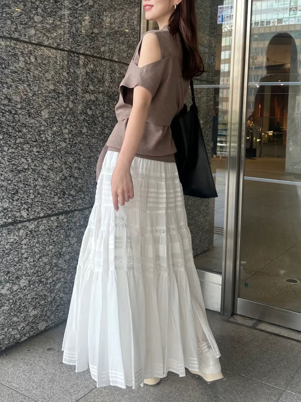 ブラウン系のニット/セーター、ホワイト系のスカートを着用したレディースの春コーディネートの2枚目の写真