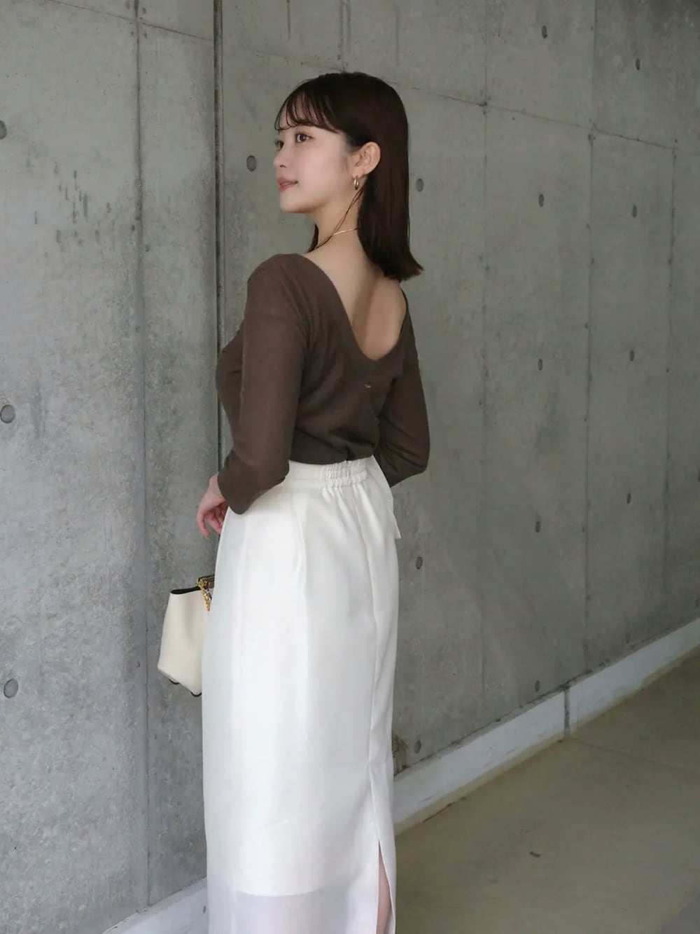 ホワイト系のテーラードジャケット、ブラウン系のTシャツ/カットソー、ホワイト系のスカートを着用したレディースの春コーディネートの3枚目の写真