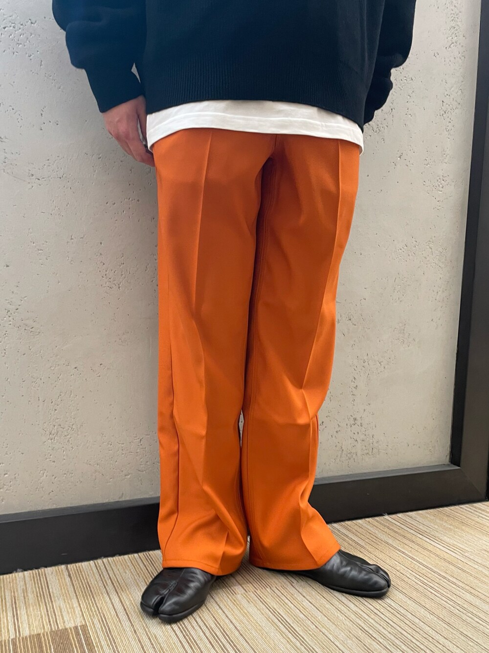 ブラック系のその他シューズ、オレンジ系のその他パンツ、ブラック系のニット/セーターを着用したメンズの冬コーディネートの2枚目の写真