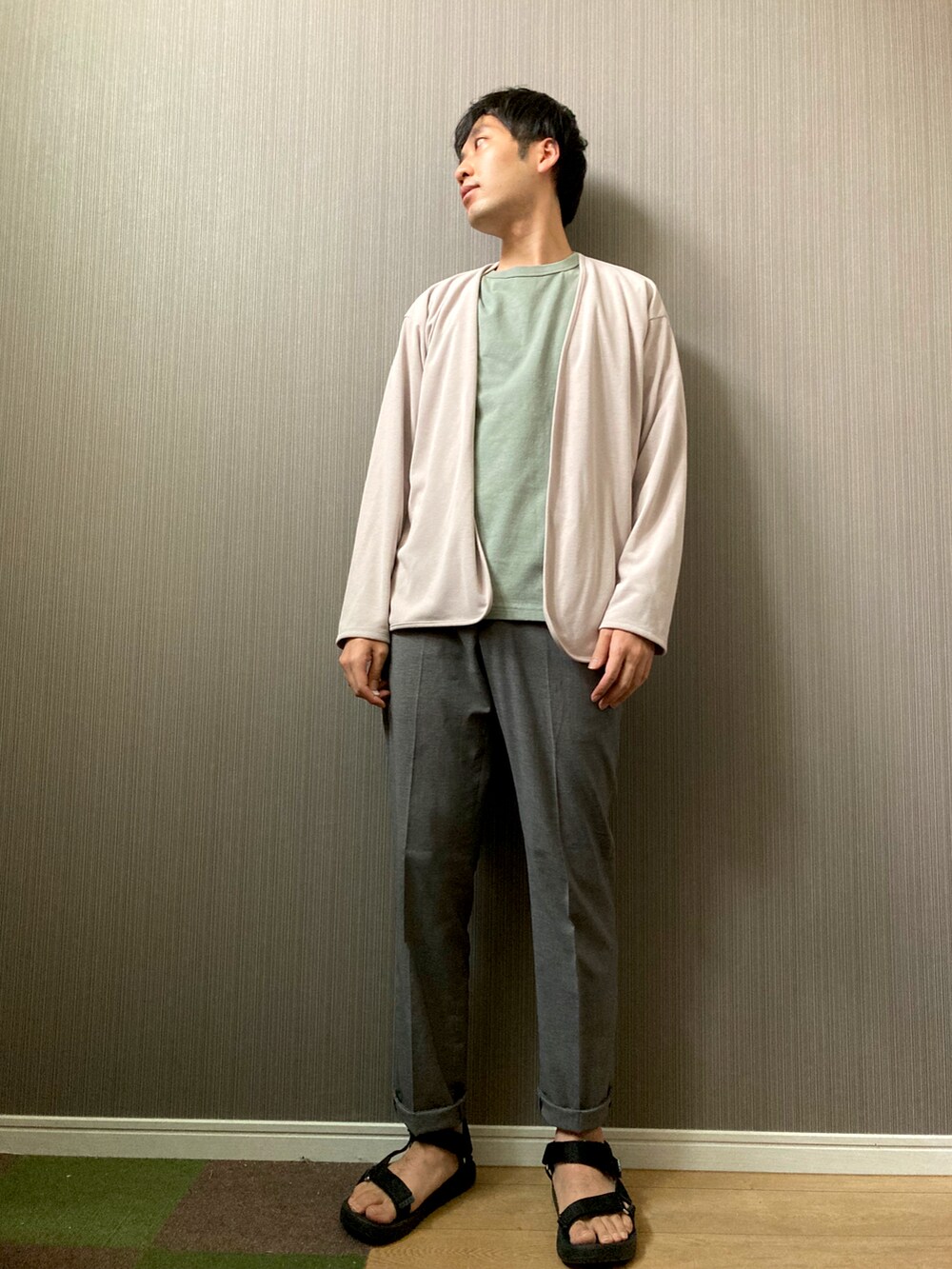 グレー系のスラックス、ブラック系のサンダル、グリーン系のTシャツ/カットソーを着用したメンズの秋コーディネートの2枚目の写真