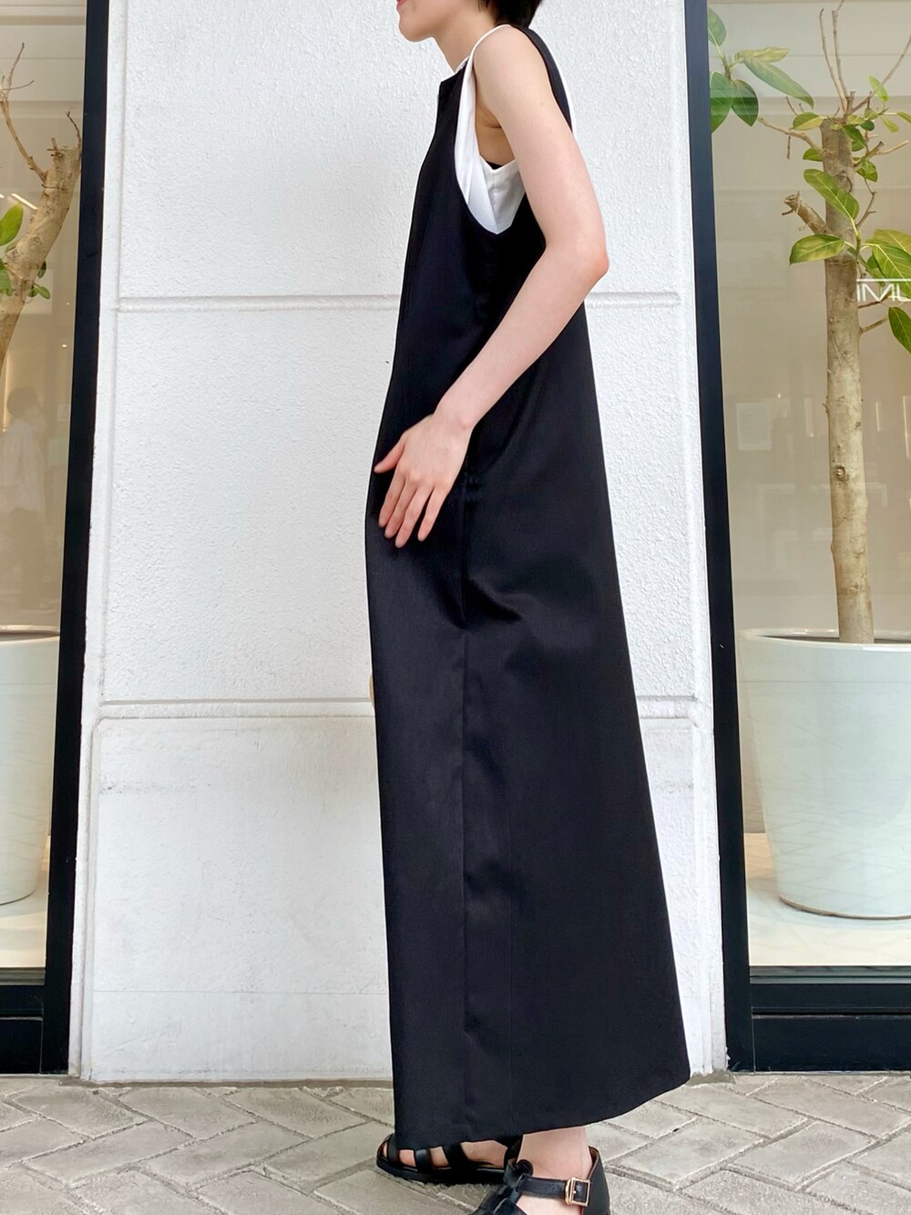 ブラック系のワンピース、ホワイト系のTシャツ/カットソー、ブラック系のサンダルを着用したレディースの春コーディネートの2枚目の写真