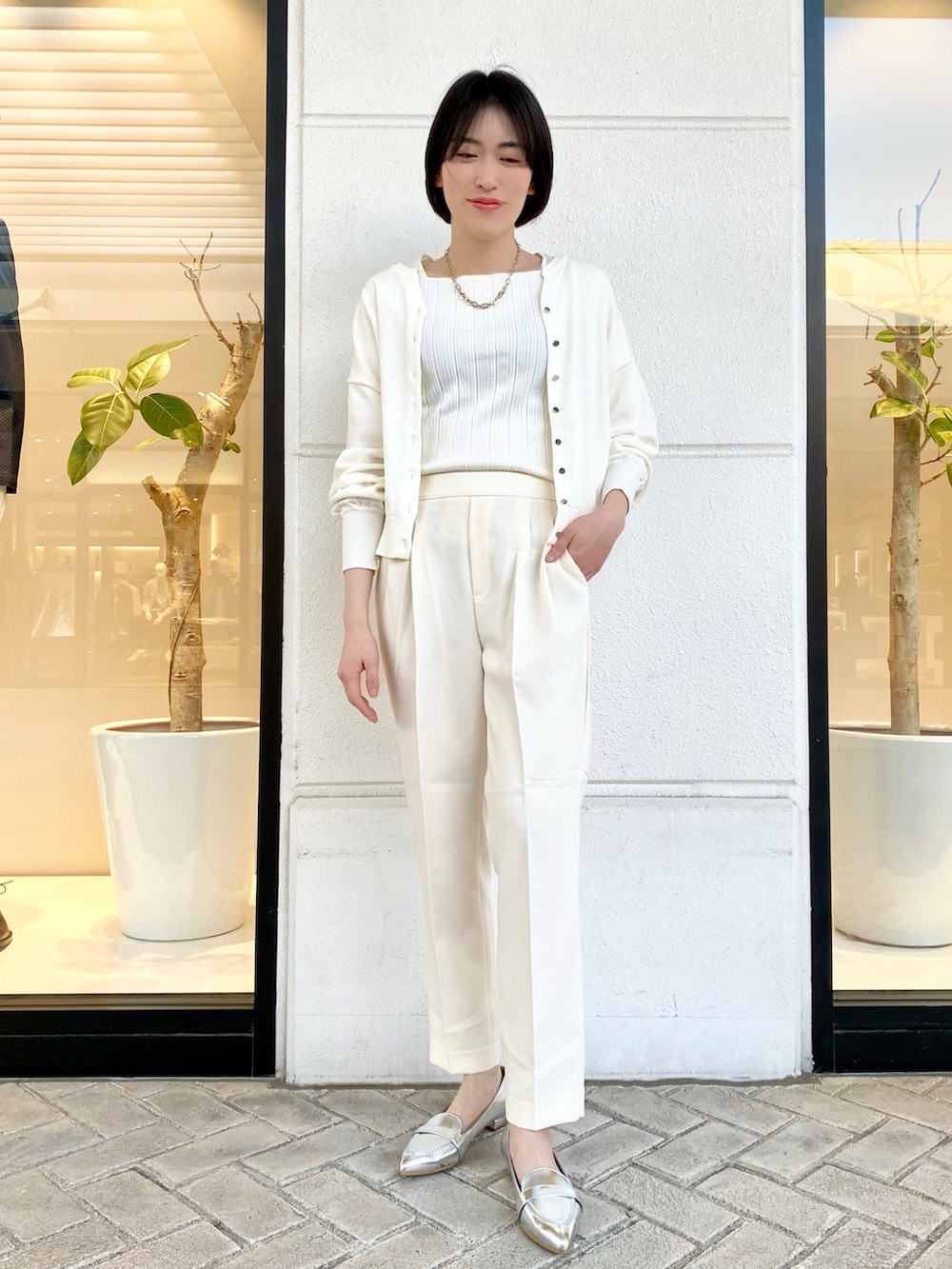 ホワイト系のカーディガン/ボレロ、ホワイト系のニット/セーター、ホワイト系のスラックスを着用したレディースの春コーディネートの2枚目の写真