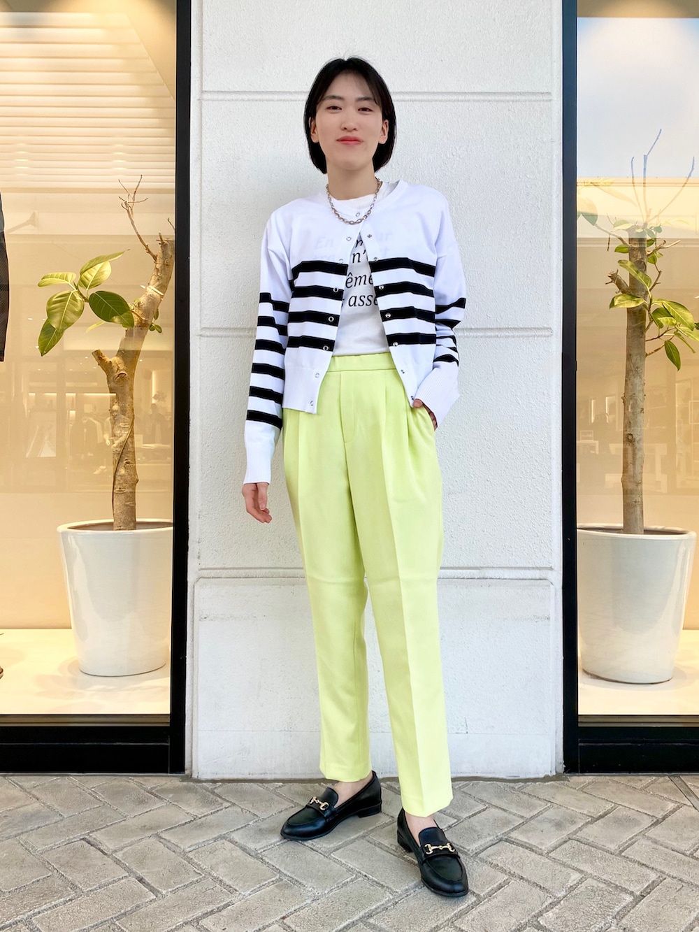 ホワイト系のカーディガン/ボレロ、ホワイト系のTシャツ/カットソー、グリーン系のスラックスを着用したレディースの春コーディネートの2枚目の写真