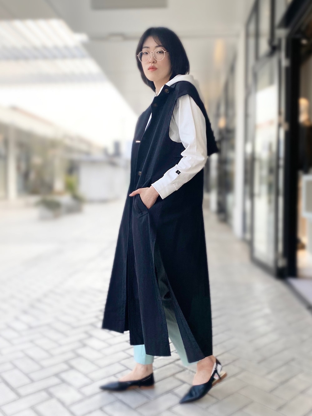 グリーン系のその他パンツ、ホワイト系のTシャツ/カットソー、ブラック系のトレンチコートを着用したレディースの春コーディネートの2枚目の写真