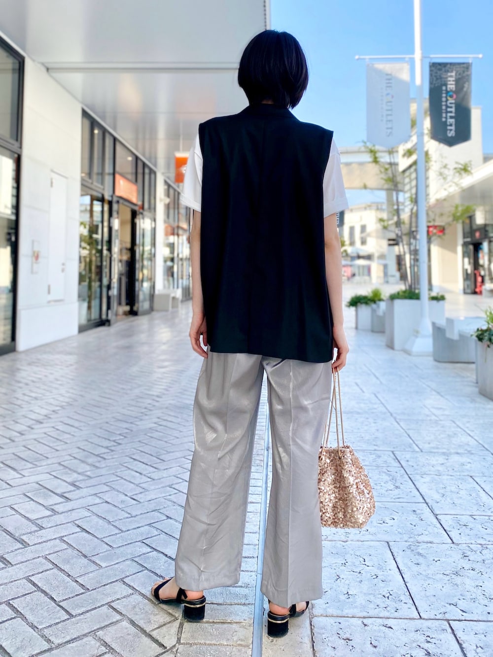 ブラック系のベスト、ホワイト系のTシャツ/カットソー、シルバー系のスラックスを着用したレディースの春コーディネートの2枚目の写真