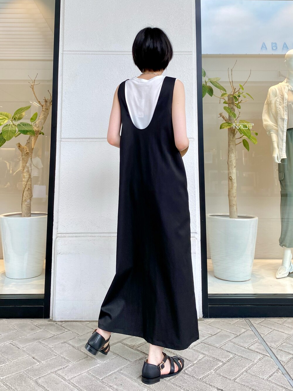 ブラック系のワンピース、ホワイト系のTシャツ/カットソー、ブラック系のサンダルを着用したレディースの春コーディネートの4枚目の写真