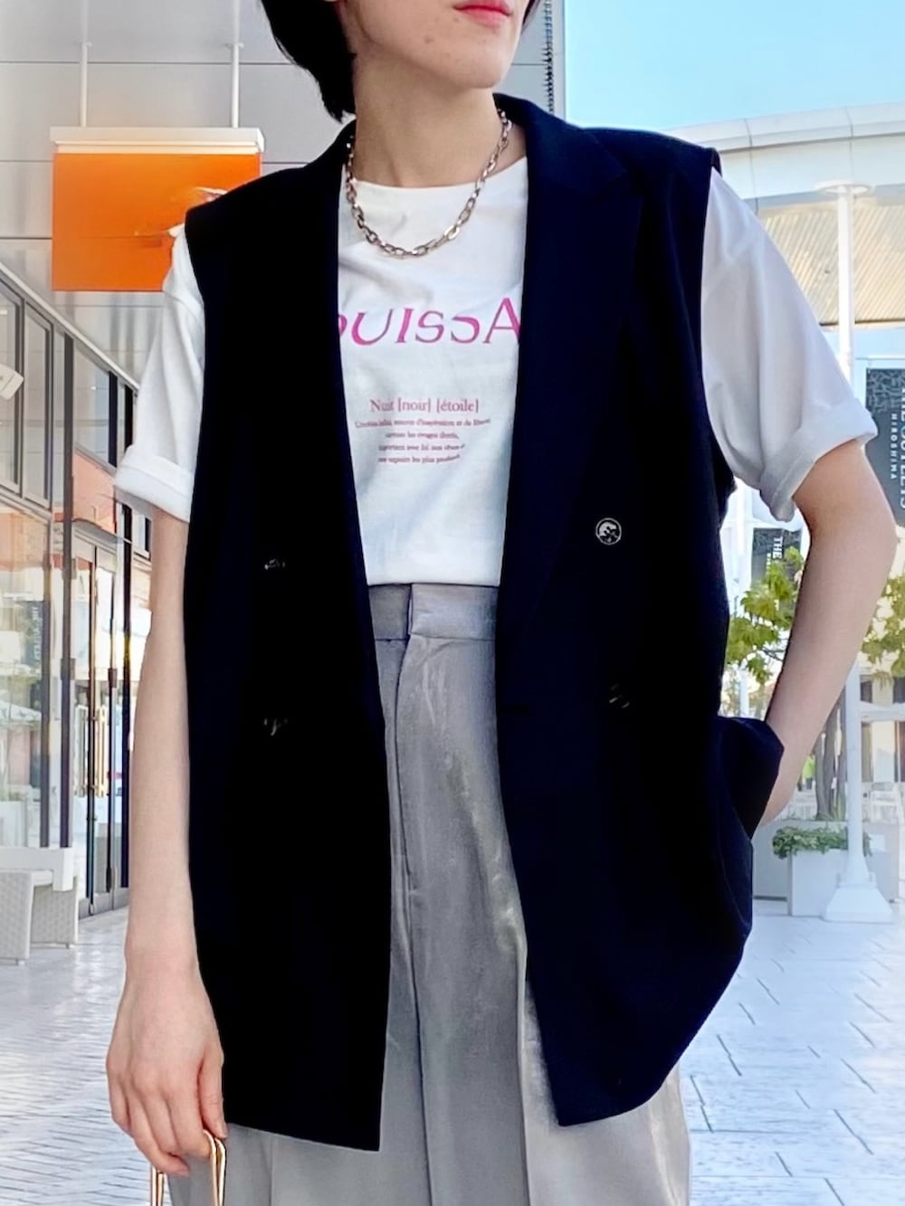 ブラック系のベスト、ホワイト系のTシャツ/カットソー、シルバー系のスラックスを着用したレディースの春コーディネートの3枚目の写真