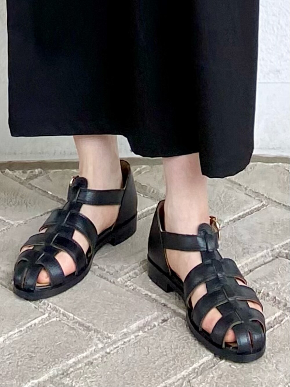 ブラック系のワンピース、ホワイト系のTシャツ/カットソー、ブラック系のサンダルを着用したレディースの春コーディネートの5枚目の写真