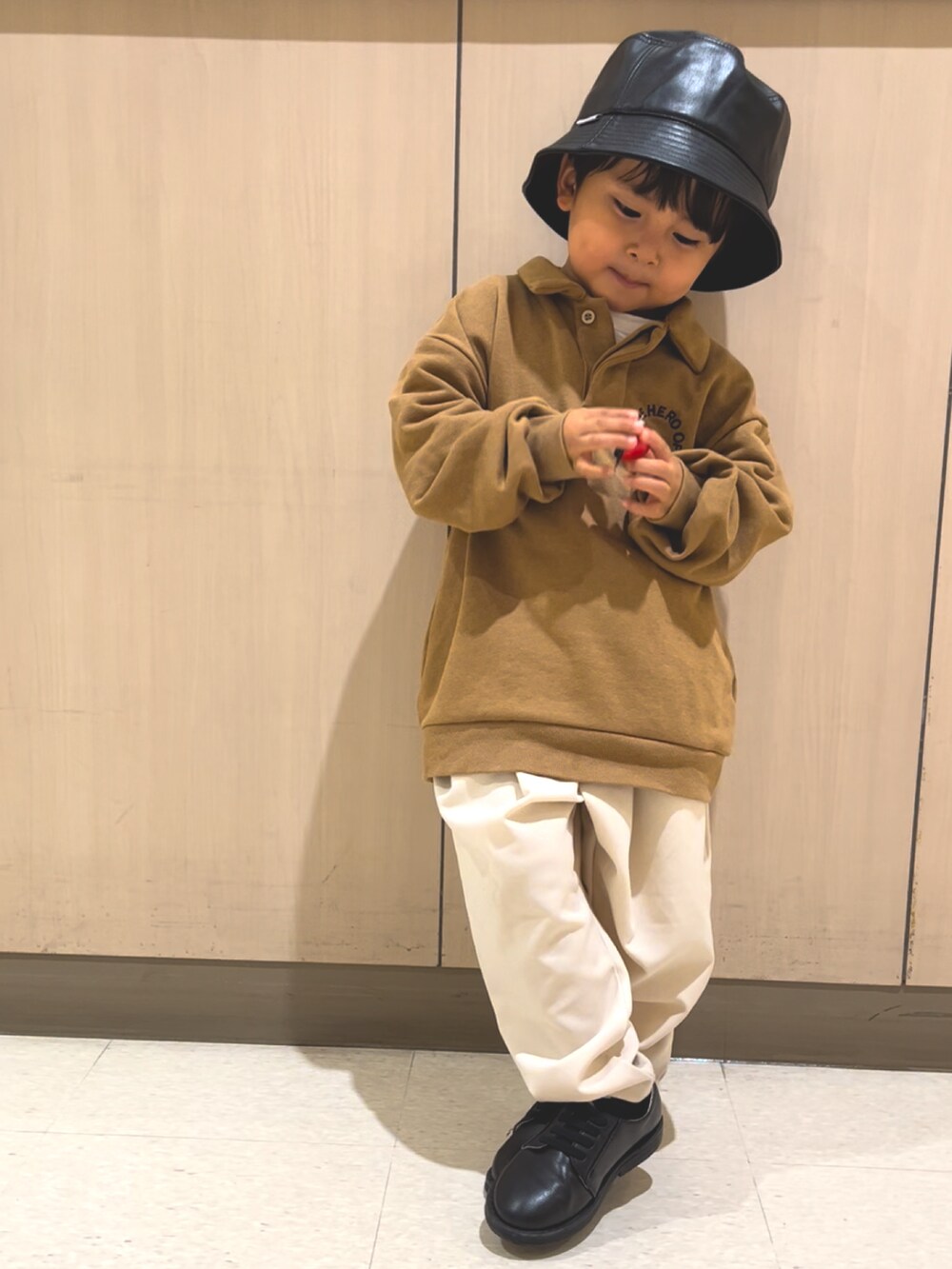 ブラウン系のトップス、ホワイト系のスラックス、ブラック系のドレスシューズを着用したキッズの秋コーディネートの3枚目の写真