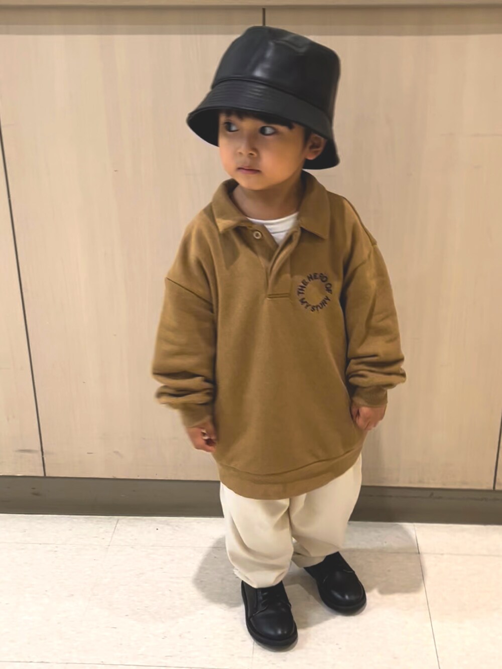 ブラウン系のトップス、ホワイト系のスラックス、ブラック系のドレスシューズを着用したキッズの秋コーディネートの2枚目の写真