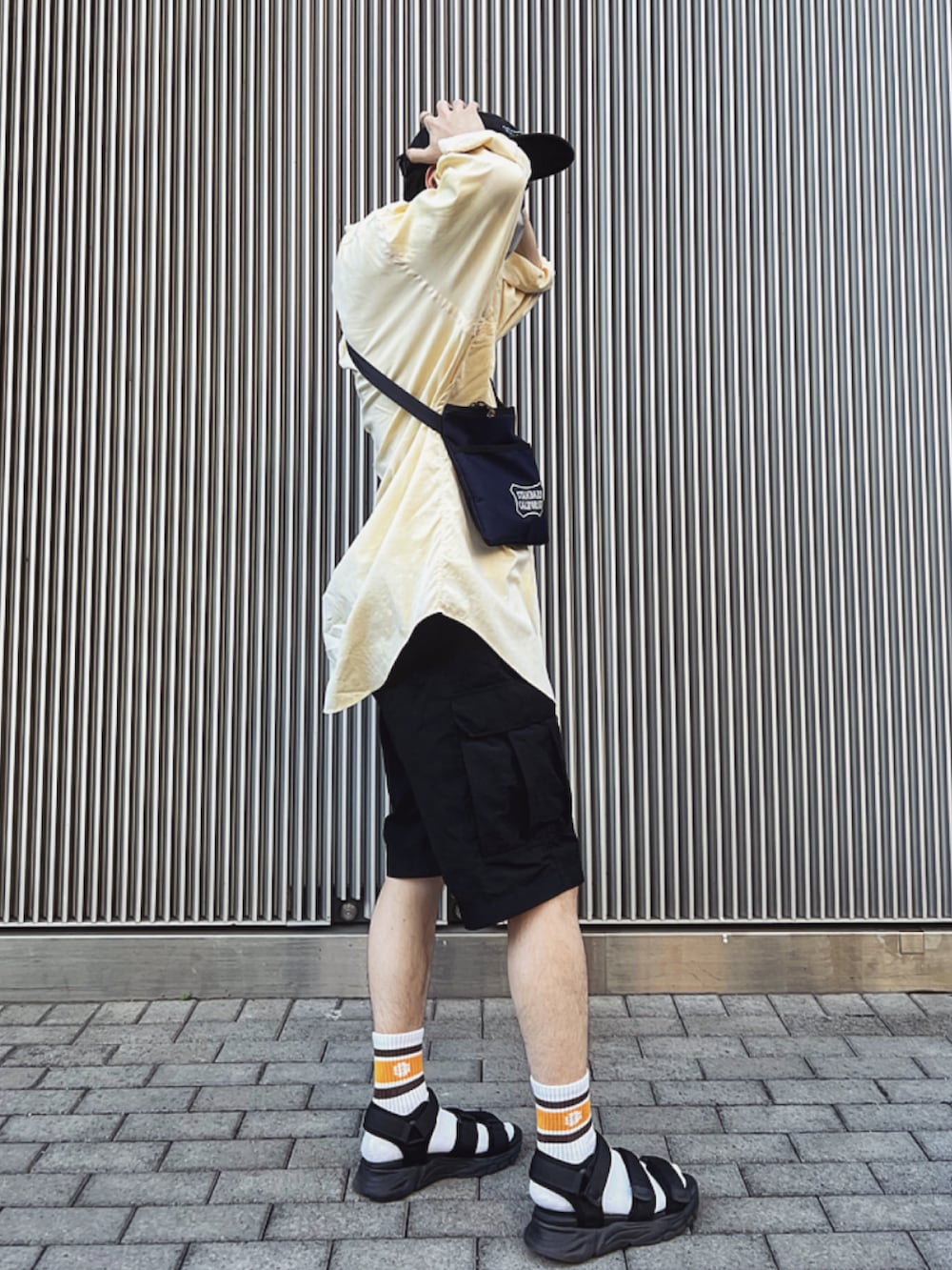 イエロー系のシャツ/ブラウス、ブラック系のカーゴパンツ、ブルー系のショルダーバッグを着用したメンズの夏コーディネートの2枚目の写真