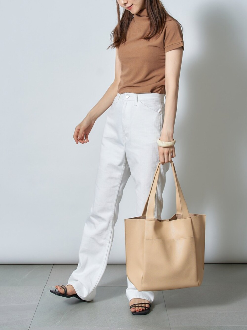 ベージュ系のトートバッグ、ブラック系のサンダル、ホワイト系のTシャツ/カットソーを着用したレディースの夏コーディネートの2枚目の写真