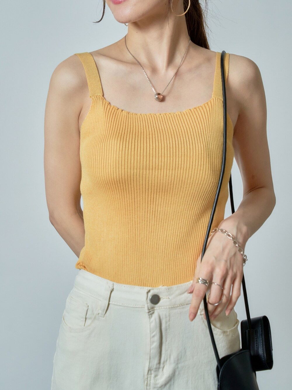 ホワイト系のデニムパンツ、イエロー系のタンクトップ、ブラック系のサンダルを着用したレディースの夏コーディネートの3枚目の写真