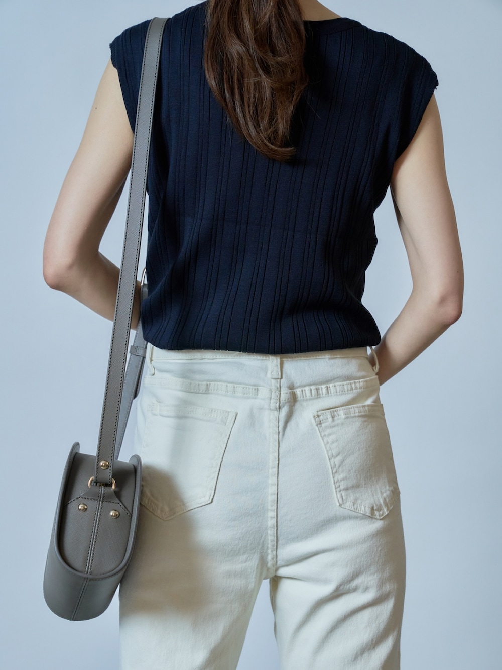 ブラック系のニット/セーター、ホワイト系のデニムパンツ、グレー系のショルダーバッグを着用したレディースの夏コーディネートの2枚目の写真