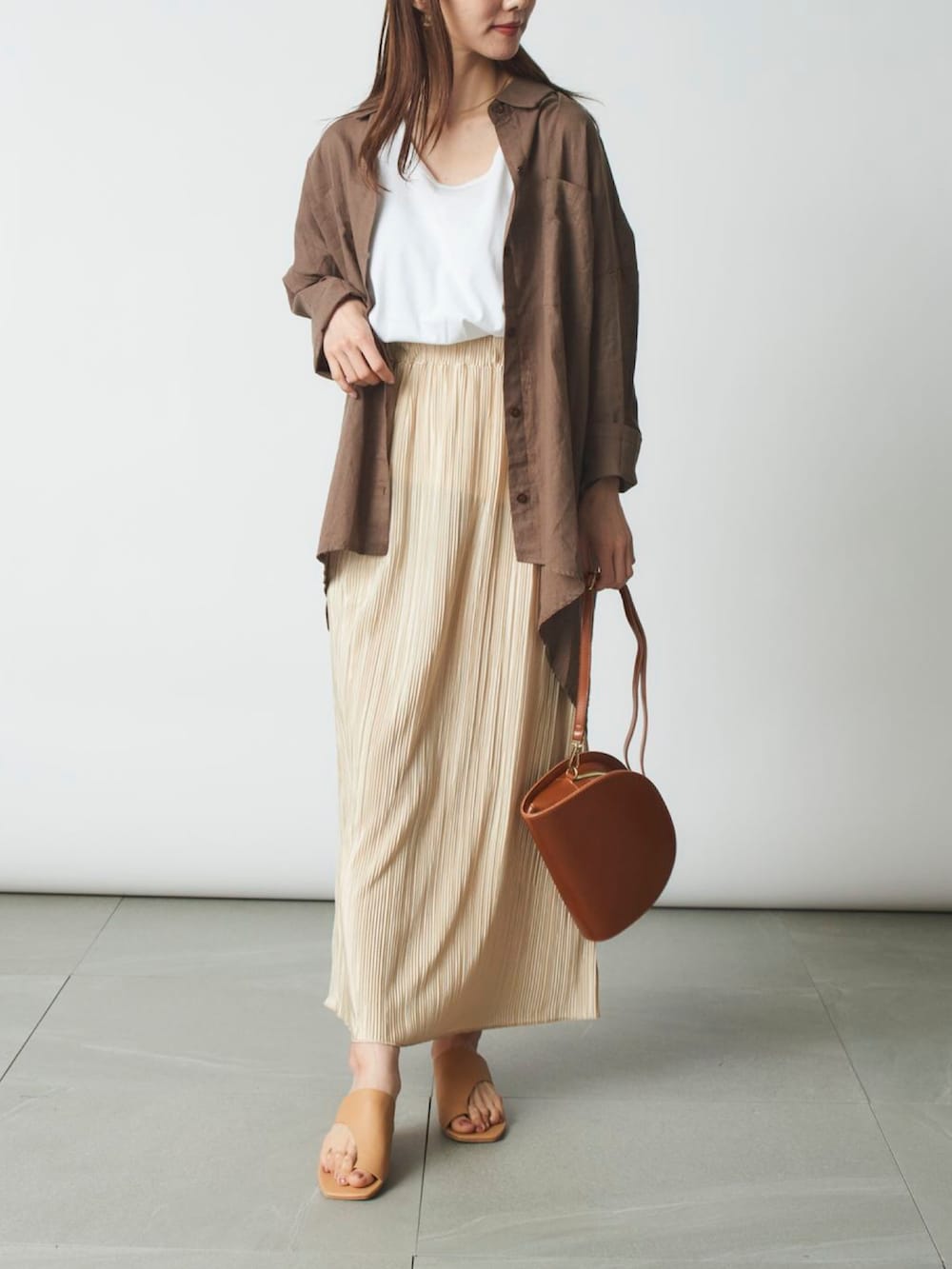 ベージュ系のシャツ/ブラウス、ホワイト系のスカート、ブラウン系のショルダーバッグを着用したレディースの春コーディネートの2枚目の写真